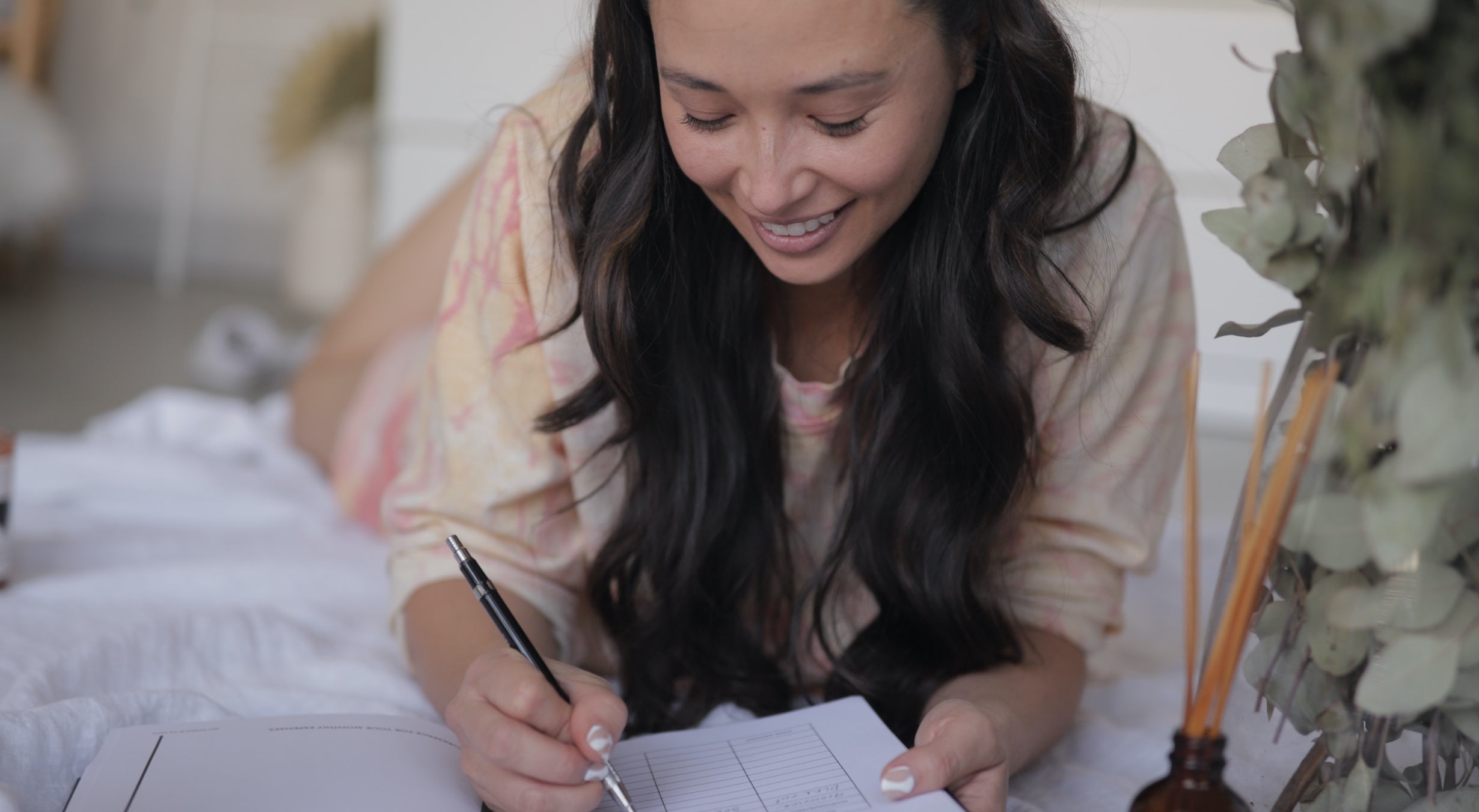 a close up picture of MSTRPLN founder Aja Dang. She's lying on the ground writing in her MSTRPLN planner. 